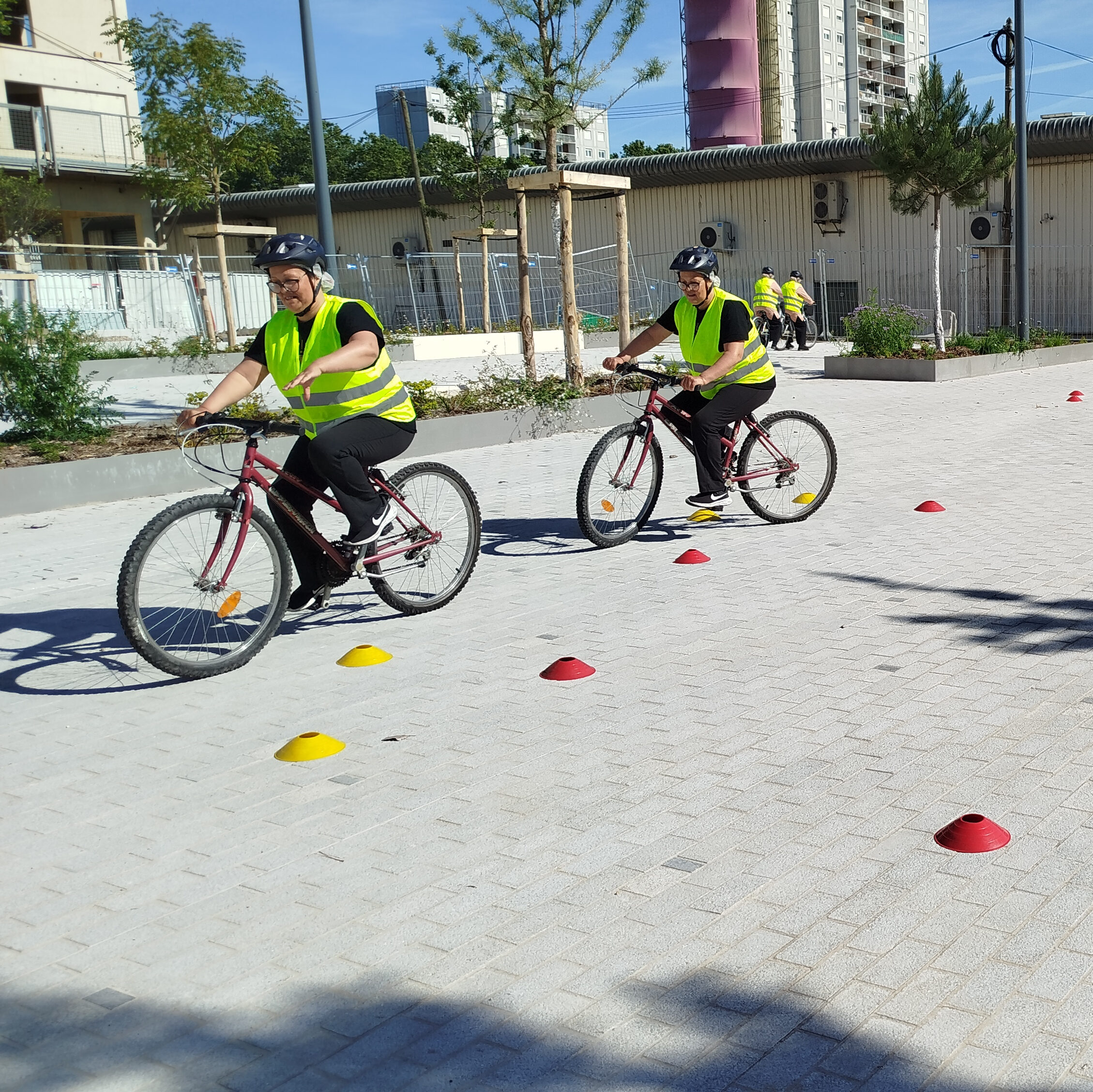 Montage photo d'une apprenante a v&eacute;lo s'entra&icirc;nant &agrave; lever la main atour de plots jaune et rouge